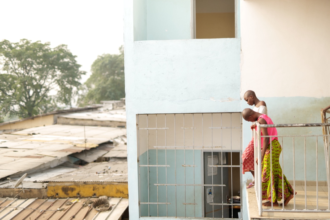 Deux jeunes femmes sur un balcon du centre, au-dessus des toits d'Abidjan